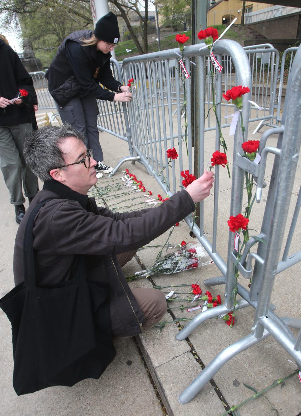 Jayland Walker protesters place red carnations on the security fence in front of the Stubbs Justice Center on Monday, April 24, 2023 in Akron.