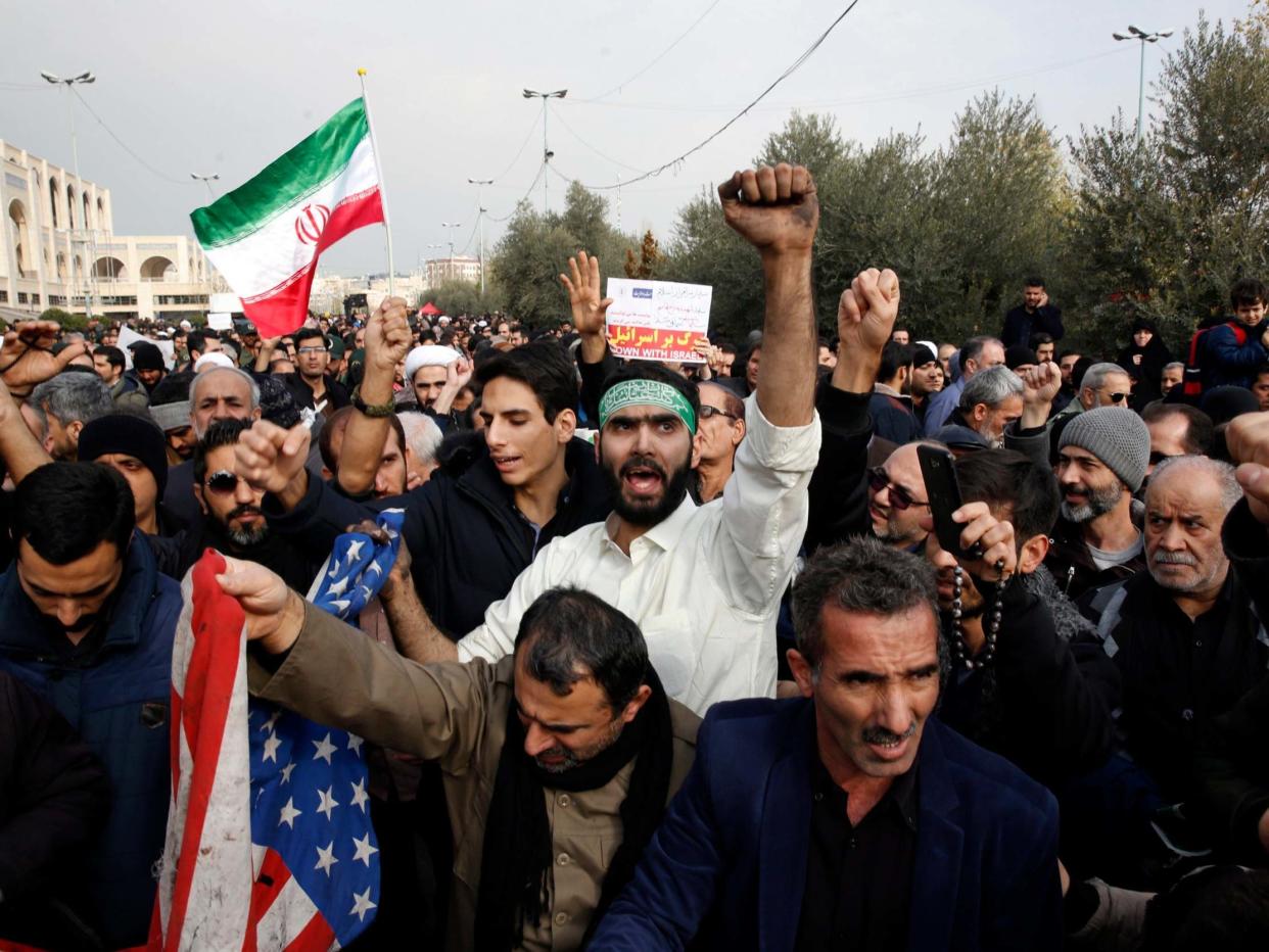 Iranians deface a US flag as thousands of people take to the streets to mourn the death of Soleimani: EPA/ABEDIN TAHERKENAREH