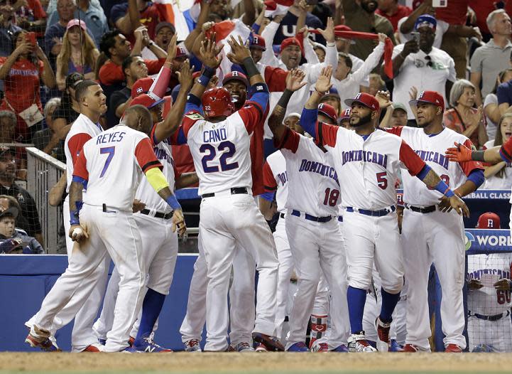 Dominican Republic's Robinson Cano (22) is met by his teammates after scoring on a single by Carlos Santana. (AP)