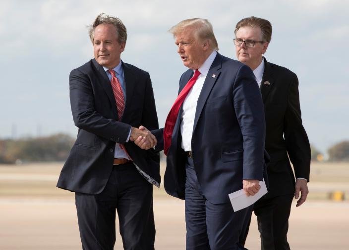 President Donald Trump is greeted by Texas Attorney General Ken Paxton, left, and Lt. Gov. Dan Patrick during a 2019 visit to Austin. Trump reiterated his support for Paxton on Saturday.