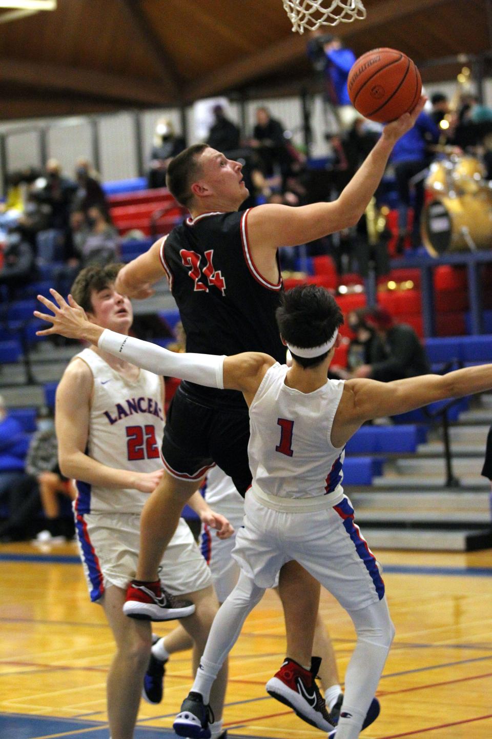 Thurston’s Jake Newell goes up for a reverse layup over Churchill’s Bugsy Jensen during Friday’s Midwestern League basketball game.