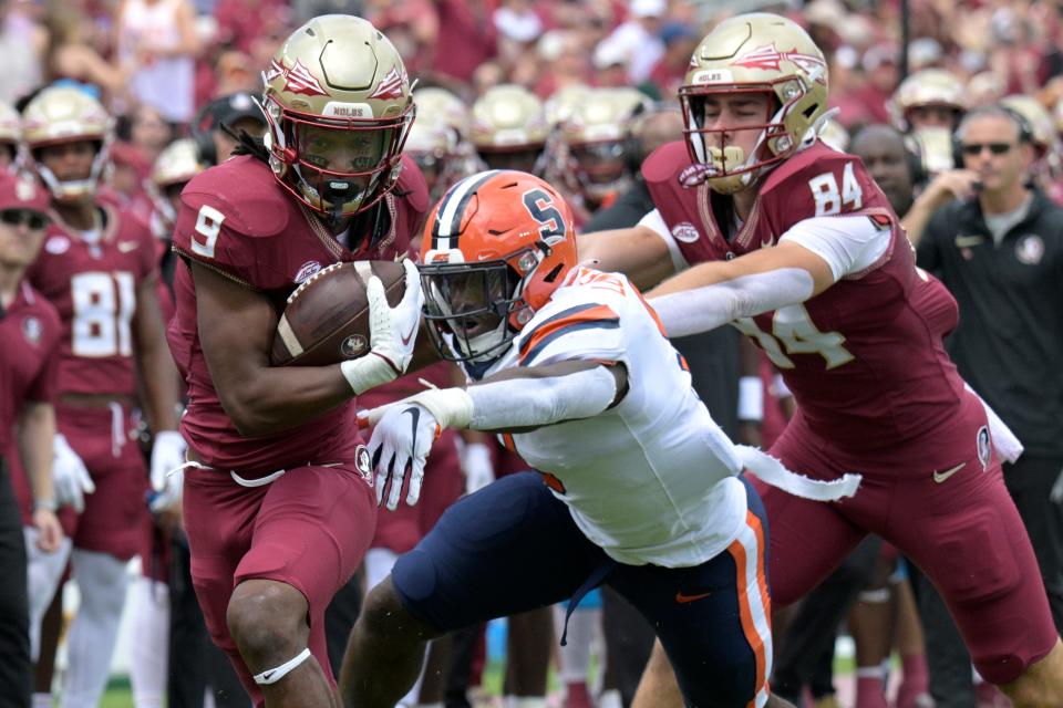 Florida State running back Lawrance Toafili (9) rushes for yardage past Syracuse linebacker Leon Lowery Jr. as FSU tight end Kyle Morlock (84) helps block during the first half of an NCAA college football game, Saturday, Oct. 14, 2023, in Tallahassee, Fla.