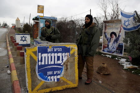Israeli soldiers stand next to a concrete barrier as they guard near a bus stop in the Gush Eztion Jewish settlement bloc in the West Bank January 27, 2016. REUTERS/Amir Cohen