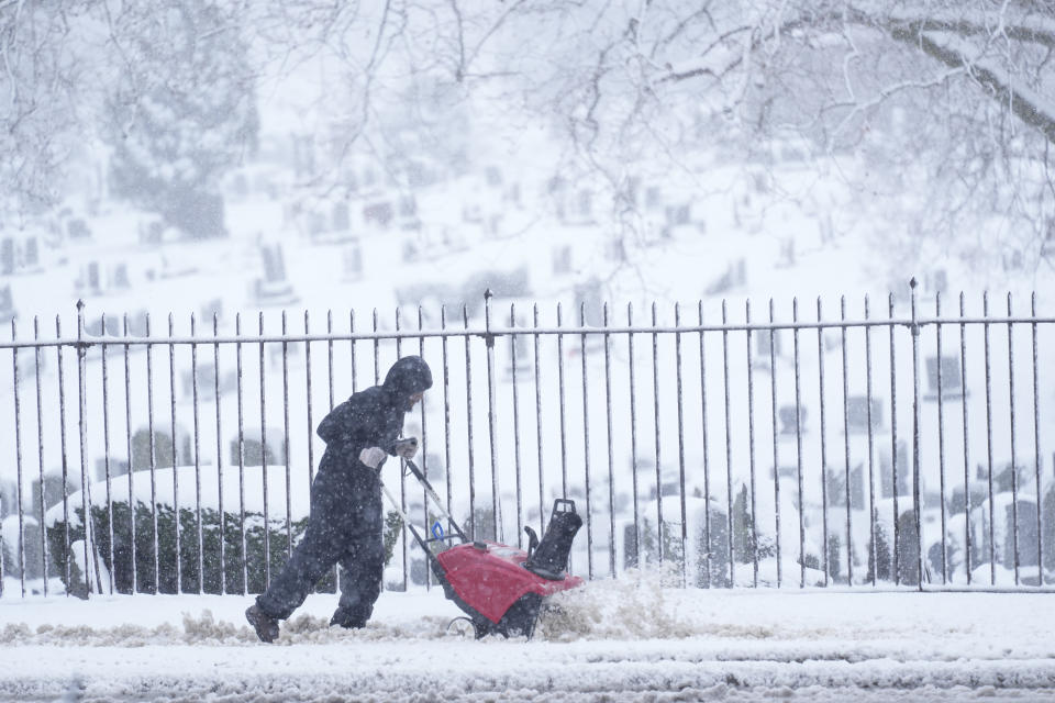 A person works to clear wet and heavy snow from a sidewalk during a winter storm in Philadelphia, Tuesday, Feb. 13, 2024. (AP Photo/Matt Rourke)