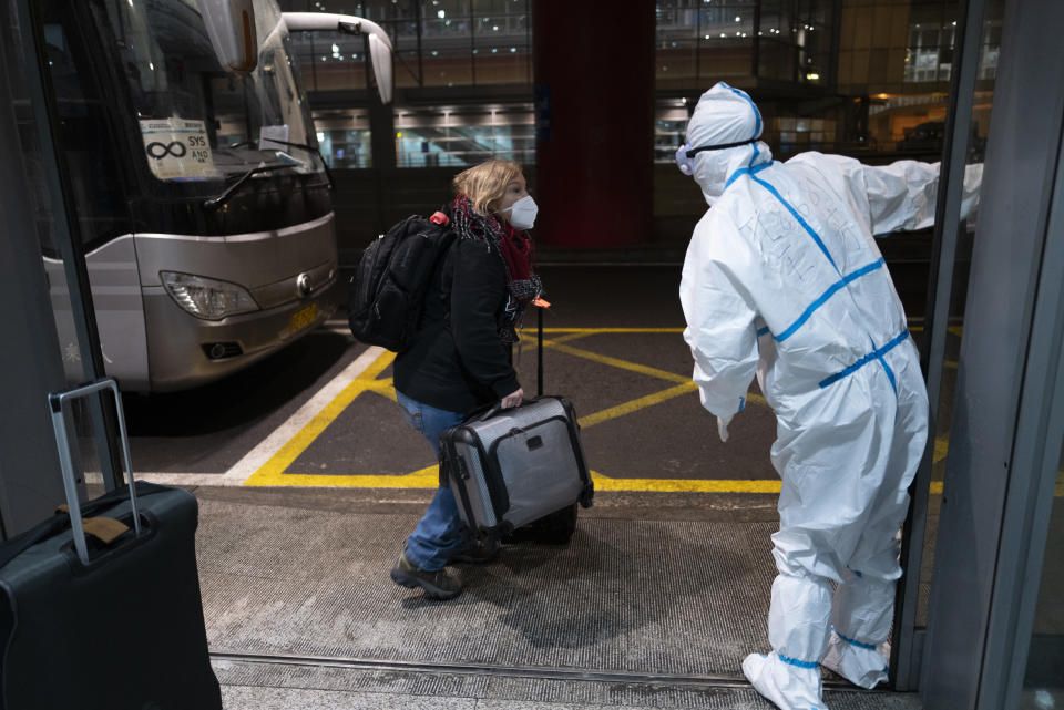 FILE - A passenger is directed to a bus by an Olympic worker wearing protective gear at the Beijing Capital International Airport ahead of the 2022 Winter Olympics in Beijing, Jan. 24, 2022. (AP Photo/Jae C. Hong, File)