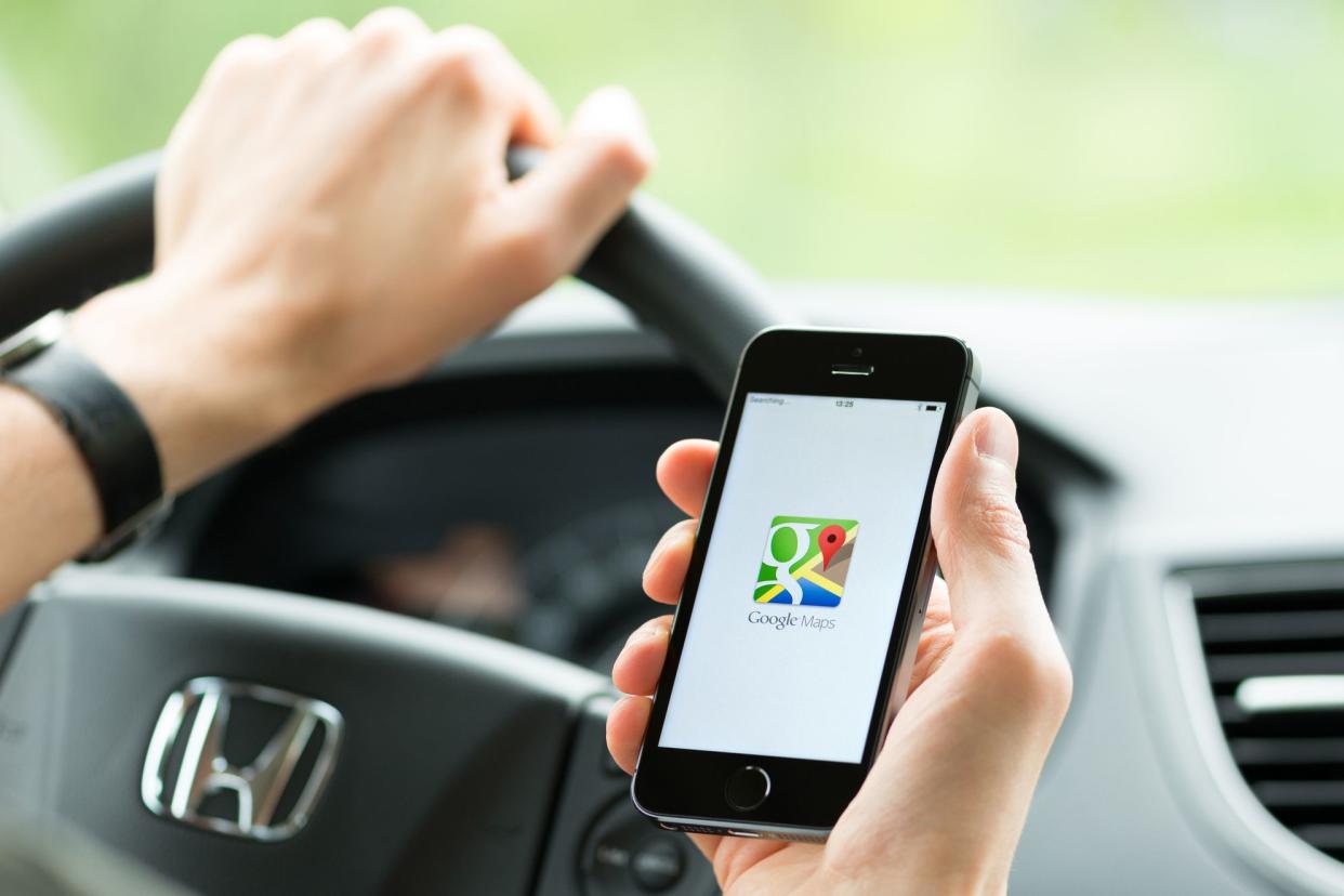 Man in the car planning a route using a Google Maps application on Apple iPhone 5S