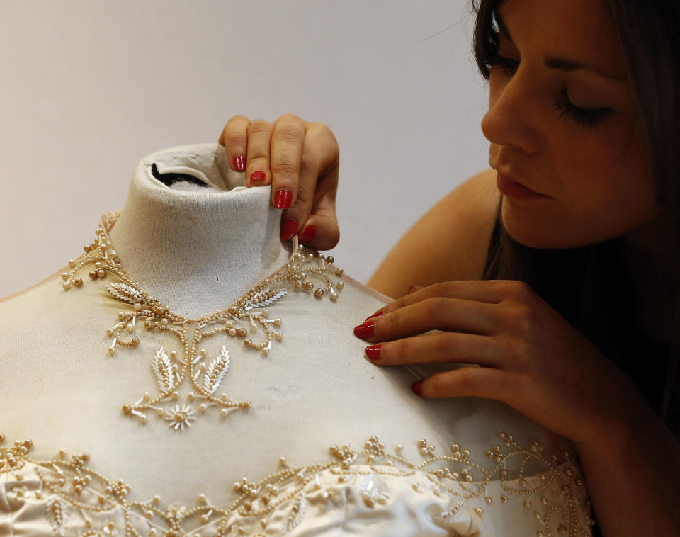 A Christie's employee adjusts Elizabeth Taylor's first wedding dress, designed by the legendary costume designer Helen Rose, at the auction house Chriestie's in London, Wednesday, June 19, 2013. The wedding dress is part of the auction 120 years of Pop Culture, which is showcasing important memorabilia dating from every decade of the past century of popular culture from the ubiquitous industries of film and music. The estimated price is 30,000 – 50,000 pound (46,000-78,000 dollars). (AP Photo/Frank Augstein)