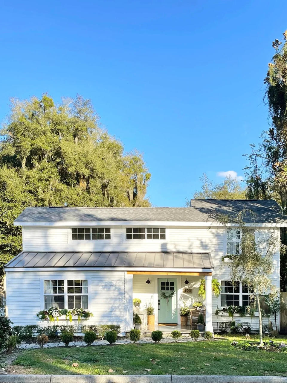 Home exterior painted cream with front yard and flowerboxes.