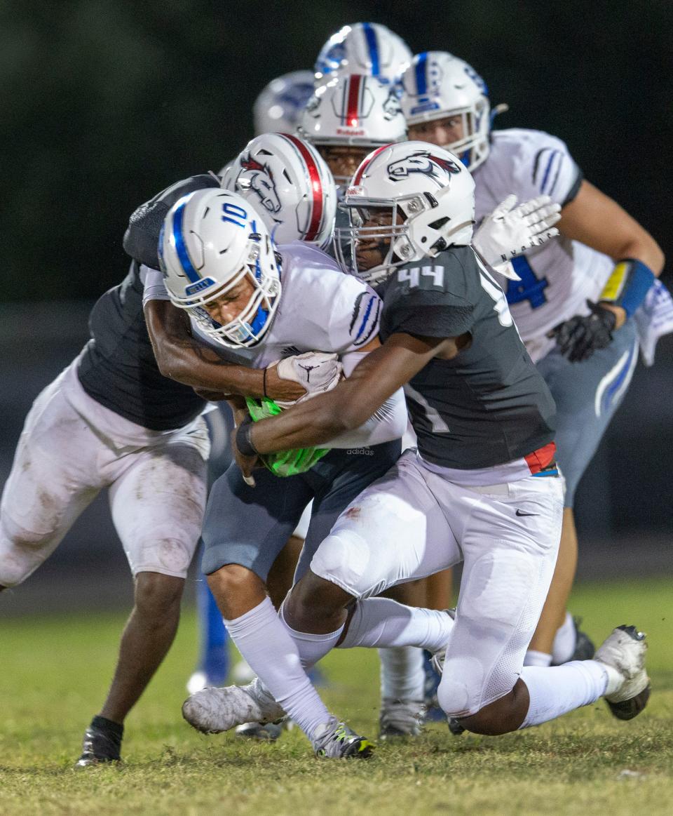 Wellington's Kevin Liriano is tackled by Palm Beach Central's Devin Wygant, left and Isaac Antoine, right, during game in Wellington, Florida on October 28, 2022.