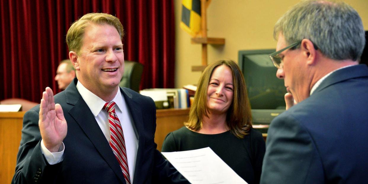 image of judge holding up right hand with wife beside him