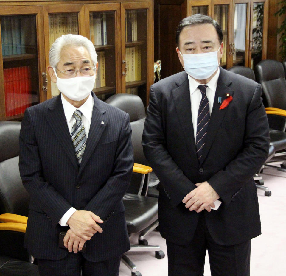 Japan's Industry Minister Hiroshi Kajiyama, right, and Suttsu Mayor Haruo Kataoka stand together during their meeting at the Ministry of Economy, Trade and Industry, in Tokyo Friday, Oct. 9, 2020. A pair of remote northern towns struggling with rapidly graining and shrinking populations signed up for a preliminary government studies to possibly build a final repository site for high-level radioactive waste from nuclear plants as a way of surviving.(Kyodo News via AP)