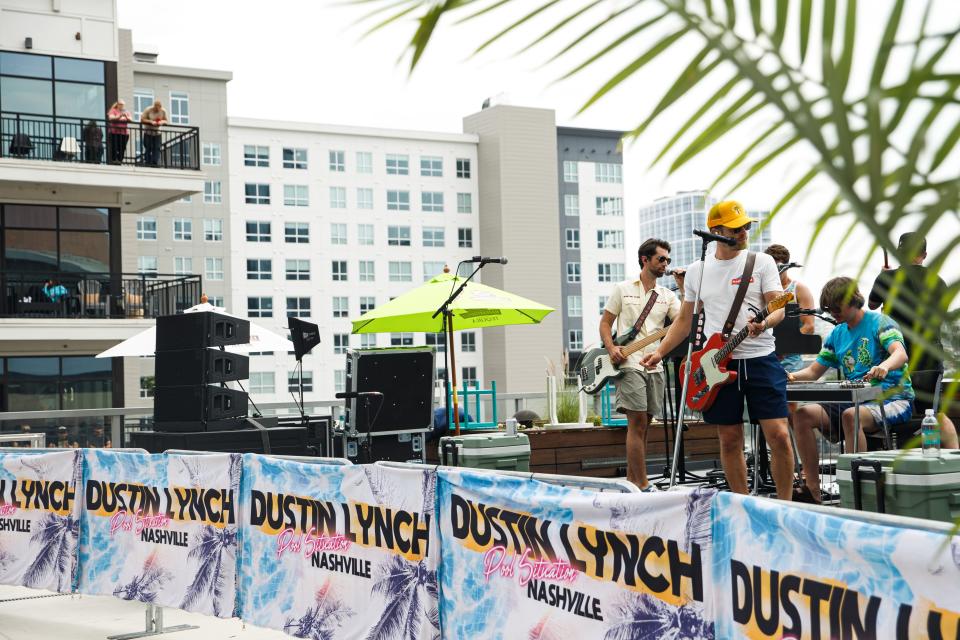 Dustin Lynch performs sound check while a couple watches him from their hotel balcony during the 50th annual CMA Fest in Nashville, Tenn. on June 10, 2023. 