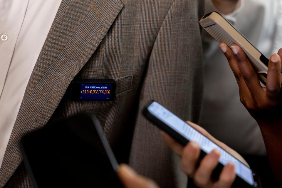 Oct 13, 2023; Washington, DC, USA; Rep. Thomas Massie, R-Ky., wears a pin displaying the national debt as he speaks to reporters before attending a meeting along with other GOP house members to work on formally elect a new speaker of the House.