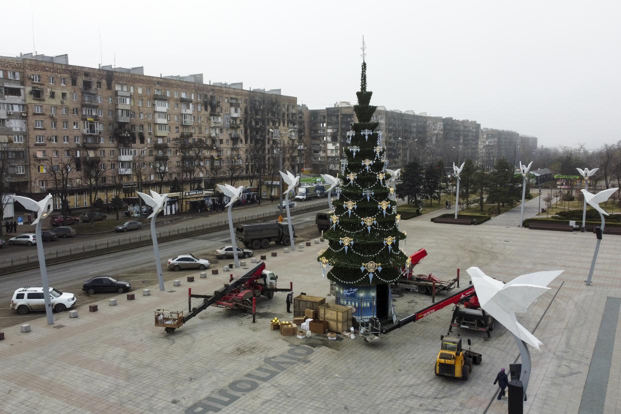 Municipal workers set a Christmas tree to decorate a square for Christmas and the New Year festivities in Mariupol, in Russian-controlled Donetsk region, eastern Ukraine, Saturday, Dec. 24, 2022. (AP Photo)