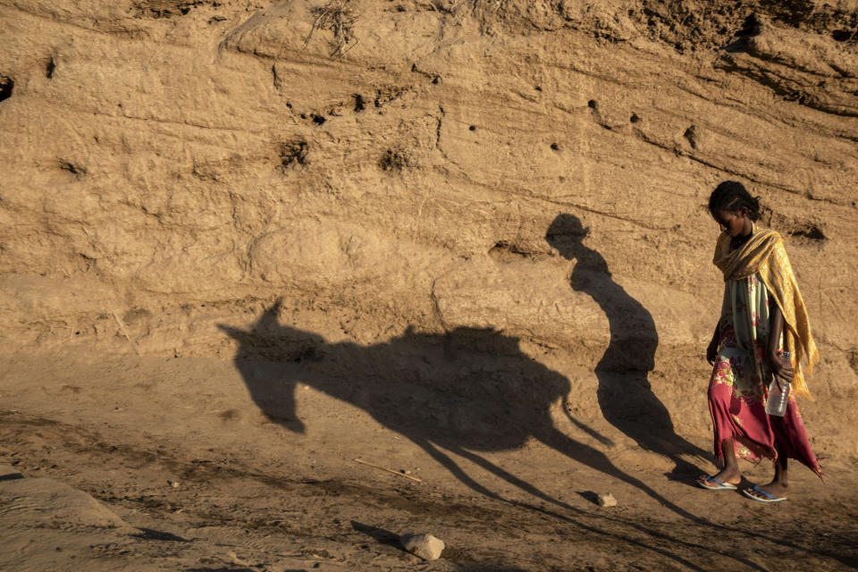 A Tigray refugee woman walks up a hill after arriving on the banks of the Tekeze River on the Sudan-Ethiopia border, in Hamdayet, eastern Sudan, Wednesday, Dec. 2, 2020. Ethiopian forces on Thursday, Dec. 3, 2020 blocked people from the country's embattled Tigray region from crossing into Sudan at the busiest crossing point for refugees, Sudanese forces said. (AP Photo/Nariman El-Mofty)