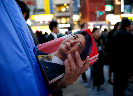 A man holds leaflets featuring an image of Japan's Prime Minister Shinzo Abe, who is also ruling Liberal Democratic Party leader, at an election campaign rally in Tokyo, Japan October 18, 2017. REUTERS/Toru Hanai