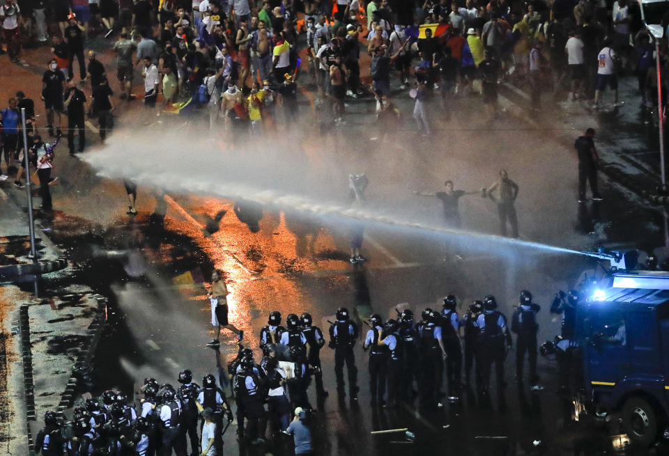 Riot police use a water canon during a charge to clear the square during protests outside the government headquarters, in Bucharest, Romania, Friday, Aug. 10, 2018. Romanians who live abroad are staging an anti-government protest calling on the left-wing government to resign and an early election.(AP Photo/Vadim Ghirda)