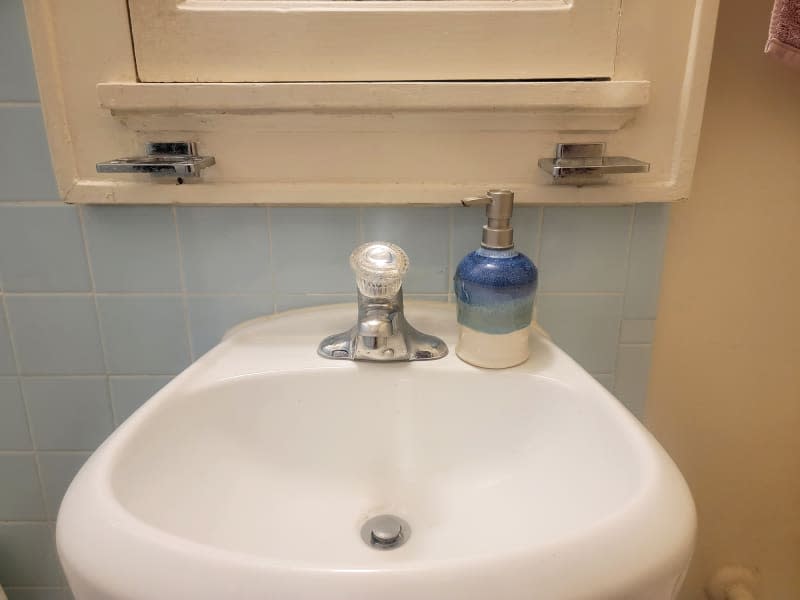 White bathroom sink with ceramic soap dispenser