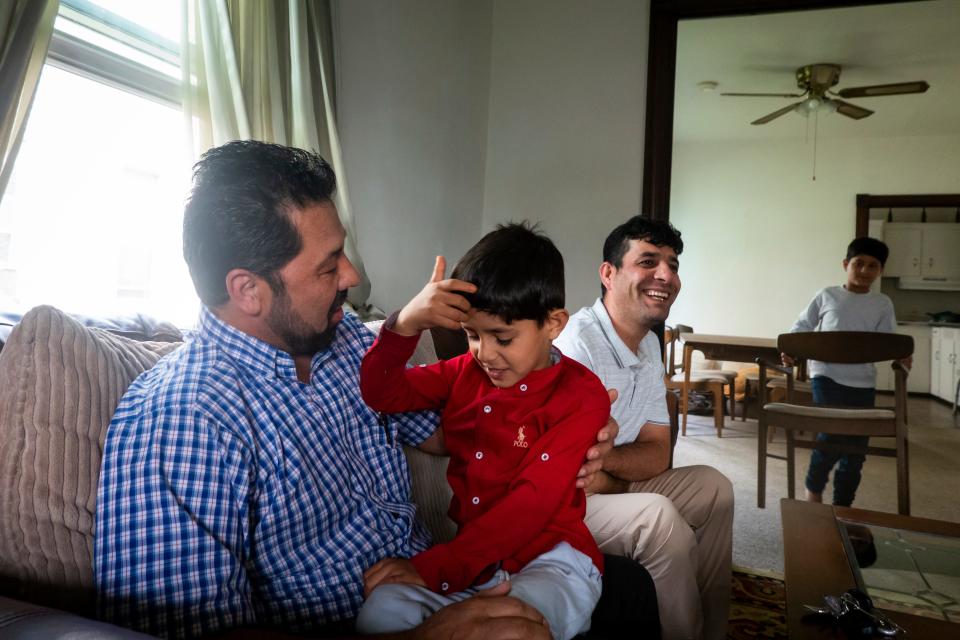 Mohammad Sadiq Alizada, left, came to the U.S. from Afghanistan in 1990. He has given Azizullah Azizyar, right, lots of advice about adjusting to life in the U.S. The Azizyar's 5-year-old son, Rashid. sits on Alizada's lap in the family's living room.