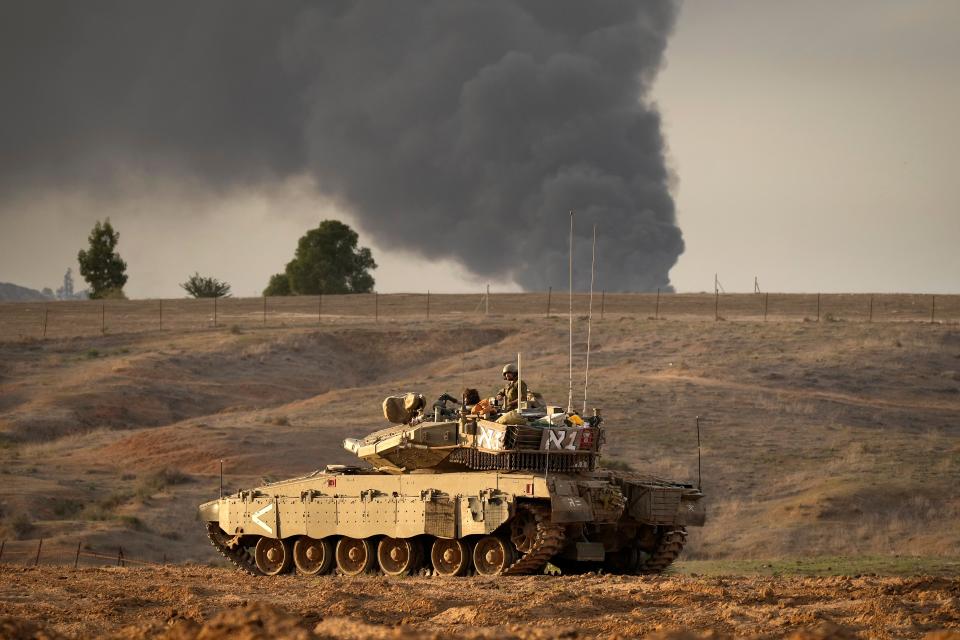 Smoke from Gaza City fills the sky in the distance as an Israeli tank heads towards the Gaza strip on 22 November 2023 in Southern Israel (Getty Images)