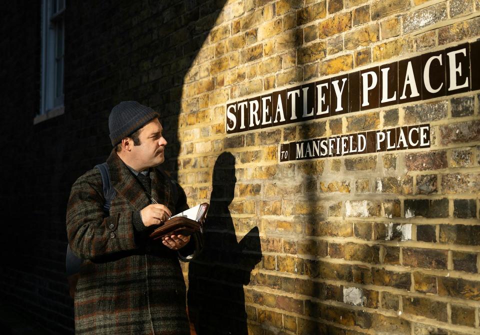 Austin on a British street, writing in a notebook.