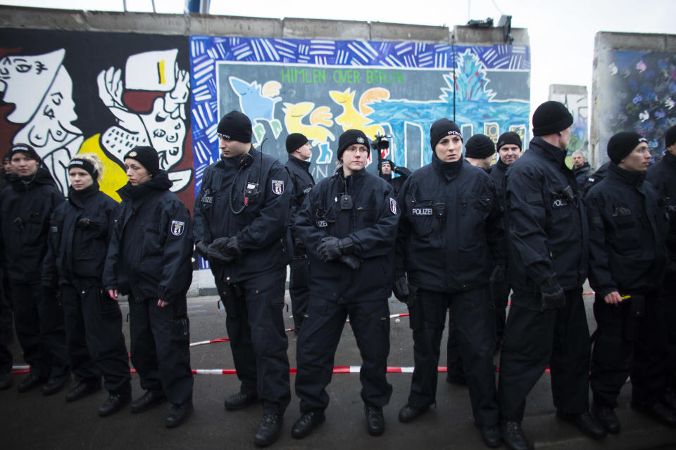 German police officers protect a part of the former Berlin Wall in Berlin, Germany, Friday, March 1, 2013. Berliners are protesting as a construction company removes a section of a historic stretch of the Berlin Wall known as the East Side Gallery to provide access to a riverside plot where luxury condominiums are being built. Since German reunification, the stretch of the wall has been preserved as a historical monument and transformed into an open air gallery painted with colorful murals, and has become a popular tourist attraction. (AP Photo/Markus Schreiber)