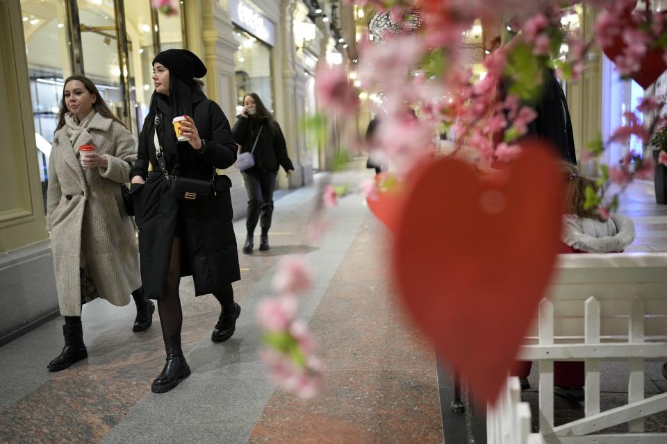 Visitors walk holding their coffee in the GUM department store in Moscow, Russia, Monday, Feb. 14, 2022. While the U.S. warns that Russia could invade Ukraine any day, the drumbeat of war is all but unheard in Moscow, where political experts and ordinary people alike don't expect President Vladimir Putin to launch an attack on the ex-Soviet neighbor. (AP Photo/Alexander Zemlianichenko)