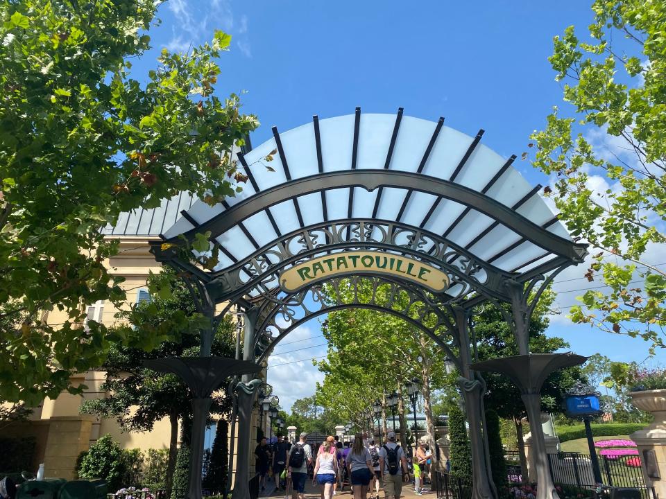 walkway to le creperie de paris at epcot with archway that reads ratatouille and trees