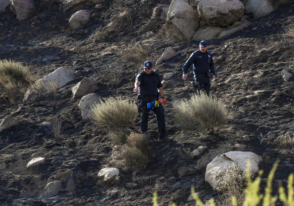 Investigators from Riverside County Fire try to find the cause of a fire that burned the mountainside above a group of trailers and vehicles near Date Ave. and F St. in Cabazon, Calif., on May 8, 2024.