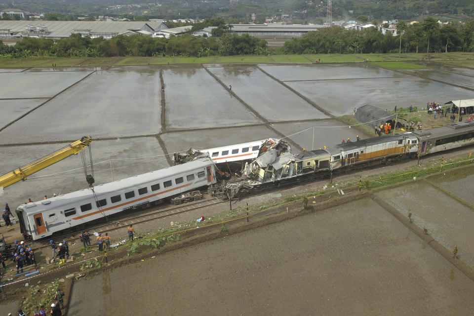 A crane tries to remove the wreckage after the collision between two trains in Cicalengka, West Java, Indonesia, Friday, Jan. 5, 2024. The trains collided on Indonesia's main island of Java on Friday, causing several carriages to buckle and overturn, officials said. (AP Photo/Achmad Ibrahim)