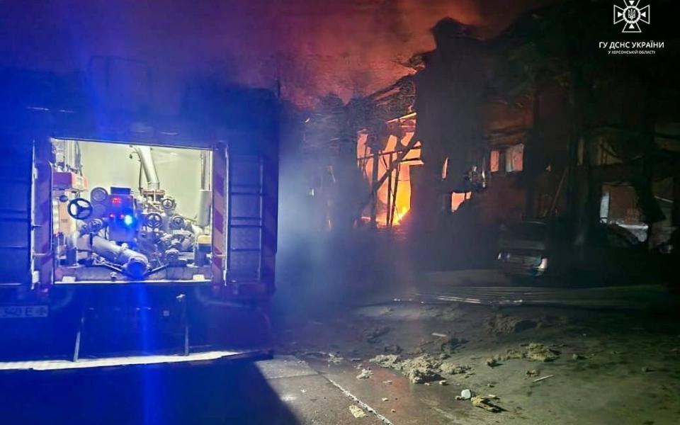 The back of a fire engine is pictured as a building blazes in the background