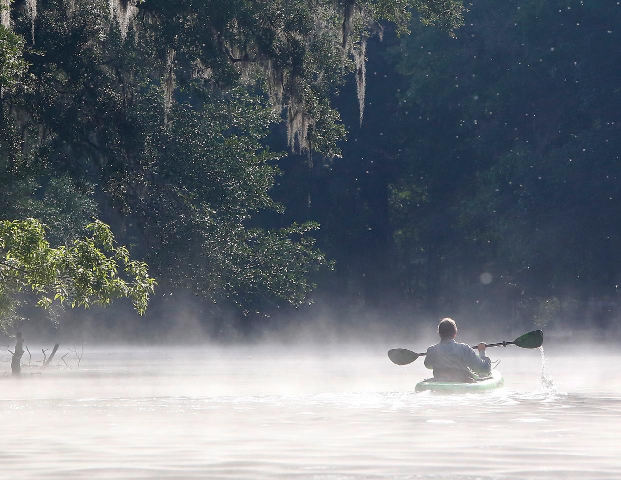 A paddler guides his kayak through the mist to River Rise on the Santa Fe River in High Springs.