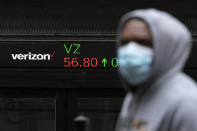 A man walks by a stock ticker displaying the cost of Verizon shares at the New York Stock Exchange, Tuesday, Feb. 23, 2021. (AP Photo/Mark Lennihan)