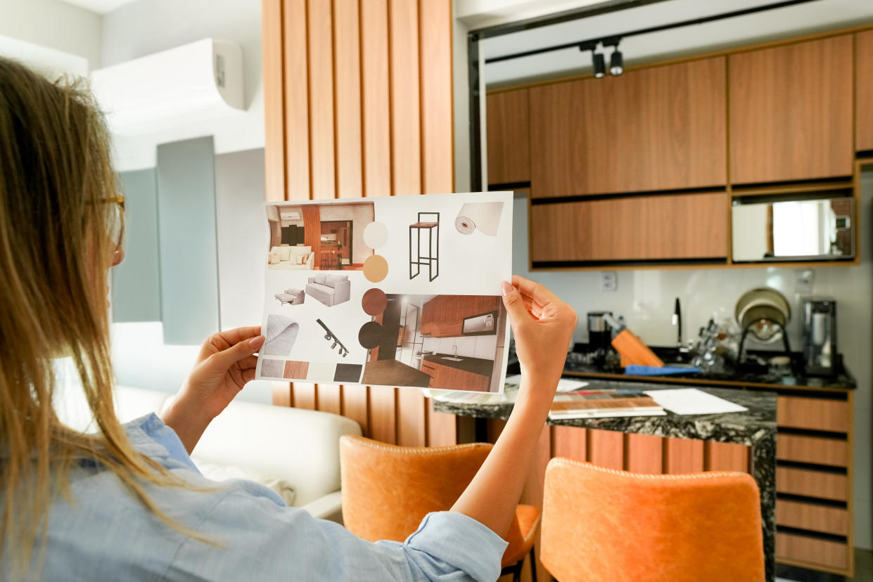 Over the shoulder view of a female architect looking at the picture of interior design sitting at home office