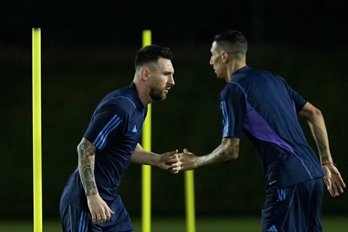 Argentina's Lionel Messi, left, and Angel Di Maria warm up during a training session Thursday in Doha, Qatar.