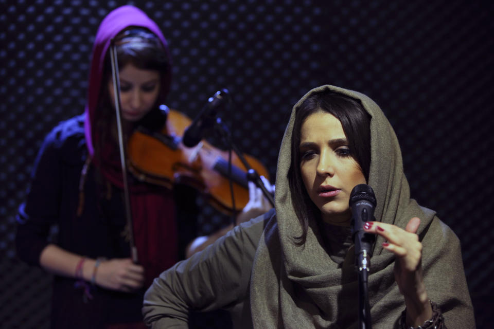 In this picture taken on Friday, Jan. 25, 2013, female Iranian back vocalist Azadeh Ettehad and violinist Nastaran Ghaffari, both members of a band called "Accolade," perform in an unauthorized stage performance in Tehran, Iran. Headphone-wearing disc jockeys mixing beats. Its an underground music scene that is flourishing in Iran, despite government restrictions. (AP Photo/Vahid Salemi)