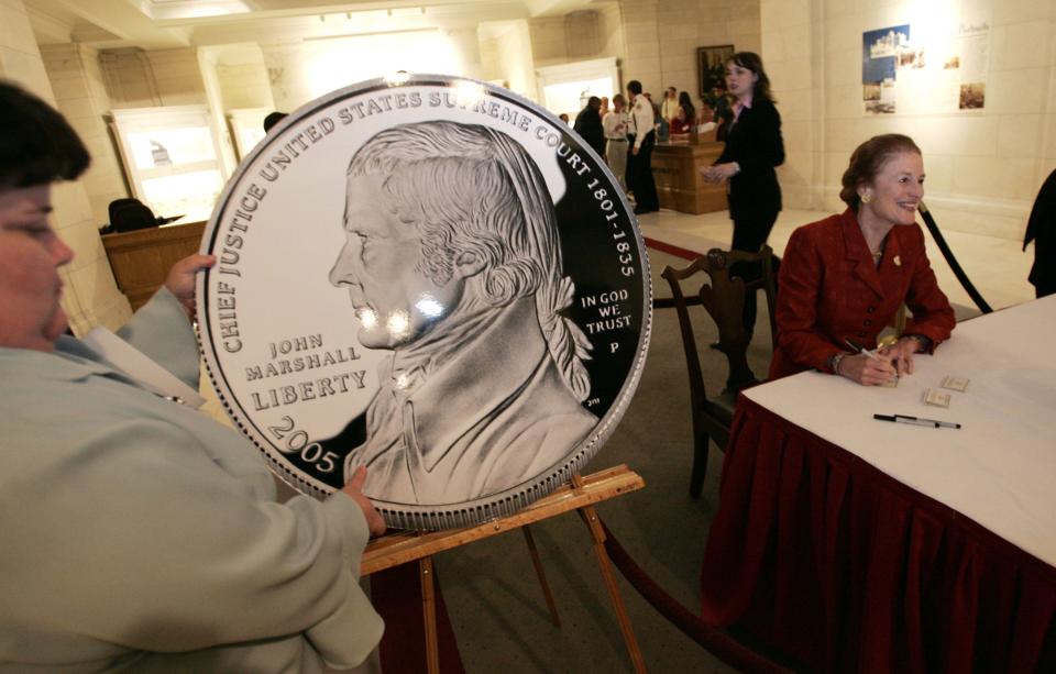 Henrietta Fore, director of the U.S. Mint (right), signs certificates of authenticity after a ceremony to unveil the Chief Justice John Marshall Silver Dollar on May 4, 2005, at the Supreme Court's Upper Great Hall in Washington, D.C.