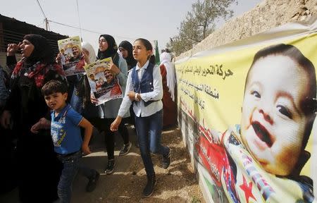 Mourners hold posters of Palestinian Riham Dawabsheh, 27 and her family as they walk past a banner depicting her 18-month-old son Ali during her funeral at Duma village near the occupied West Bank city of Nablus, September 7, 2015. REUTERS/Abed Omar Qusini/Files