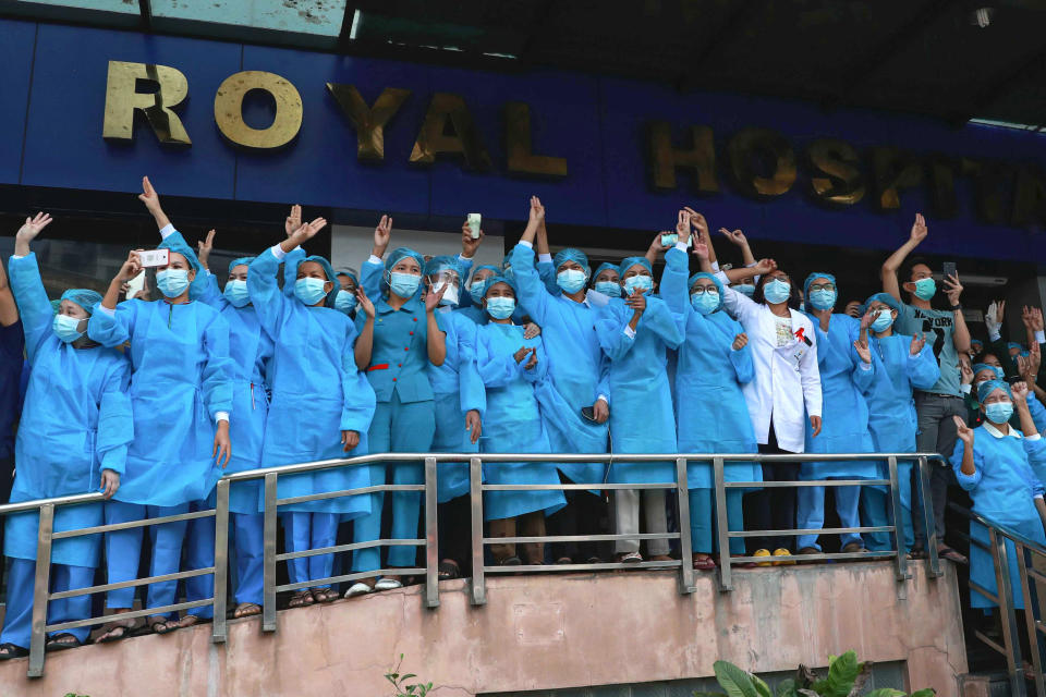 FILE - In this Sunday, Feb. 7, 2021 file photo, medical workers give the three-fingered salute outside Asia Royal Hospital as they watch protesters march in Yangon, Myanmar. Medics are particularly feared by the military because they are highly respected and well-organized, with a strong network of unions and professional groups. (AP Photo/File)