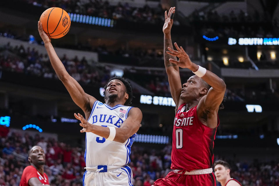 Duke's Jeremy Roach, left, goes up for a shot against North Carolina State's DJ Horne during the second half of an Elite Eight college basketball game in the NCAA Tournament in Dallas, Sunday, March 31, 2024. (AP Photo/Tony Gutierrez)