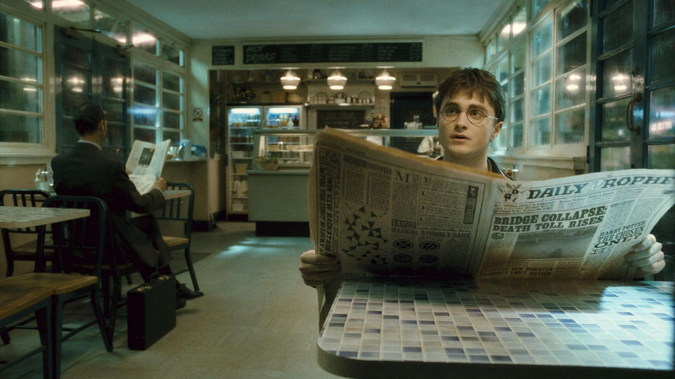 Harry sitting in a café reading a newspaper