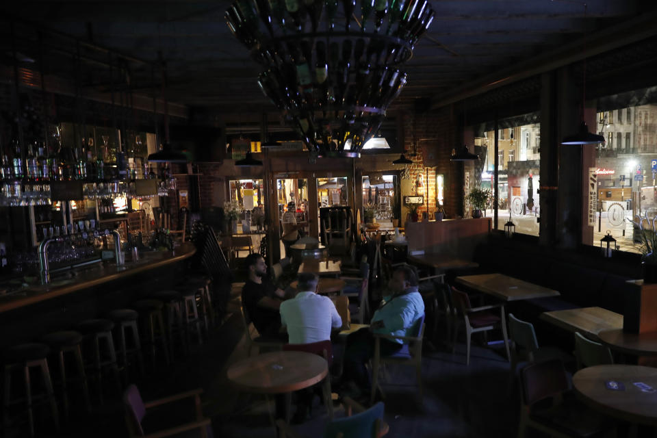 The owner and employees of Beers Bank pub sit down after closing the bar in Brussels, Wednesday, Oct. 7, 2020. Since bars in Brussels were forced to close as of Thursday for at least a month to deal with a massive surge in cases while restaurants were allowed to remain open, the big question on the streets is: when is a bar a bar and when is a bar a restaurant. (AP Photo/Francisco Seco)