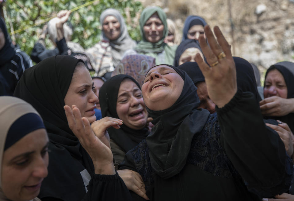Palestinian mourners cry while taking the farewell look at the body Shaukat Awad, 20 during his funeral in the West Bank village of Beit Ummar, near Hebron, Friday, July. 30, 2021. Israeli troops shot and killed the 20 year old Palestinian man, Palestinian health officials said, during clashes that erupted in the occupied West Bank following the funeral of a Palestinian boy killed by army fire the previous day. (AP Photo/Nasser Nasser)