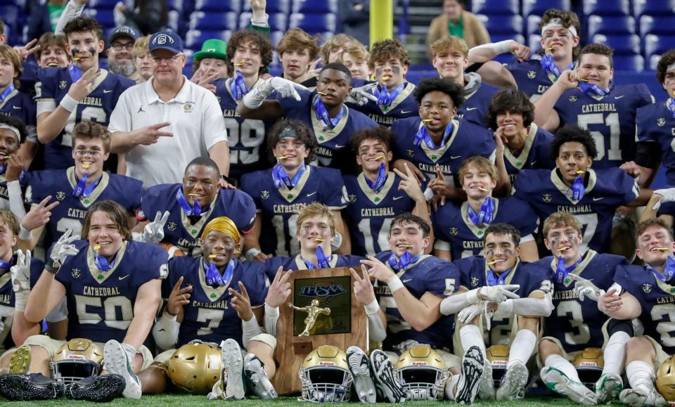 Cathedral players pose after winning a state final game Friday, Nov. 26, 2021, at Lucas Oil Stadium. The Cathedral Fighting Irish defeated the Zionsville Eagles 34-14.