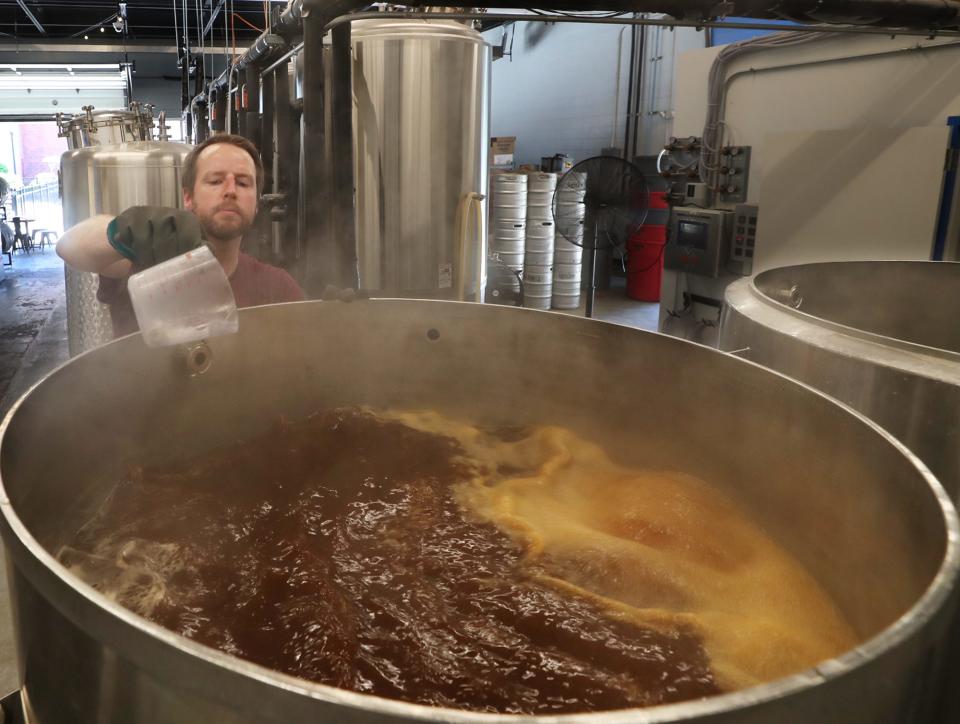Nick Law, a brewer at Ignite Brewing Co. in Barberton, adds a clearing agent to a batch of Tenacious Red in the boil kettle at the brewery. Ignite is joining breweries statewide to participate in the 2022 Ohio Pint Day.