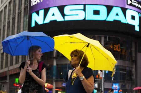 FILE PHOTO: Two women hold umbrellas as they walk past the Nasdaq MarketSite in New York's Times Square