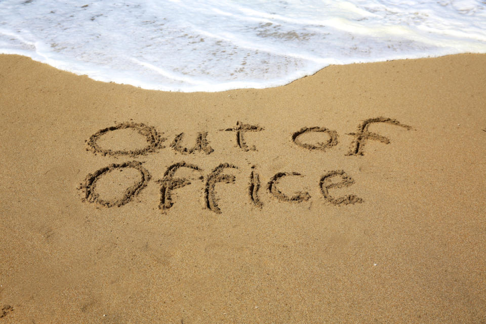 Out of office written in beach sand to signify annual leave.