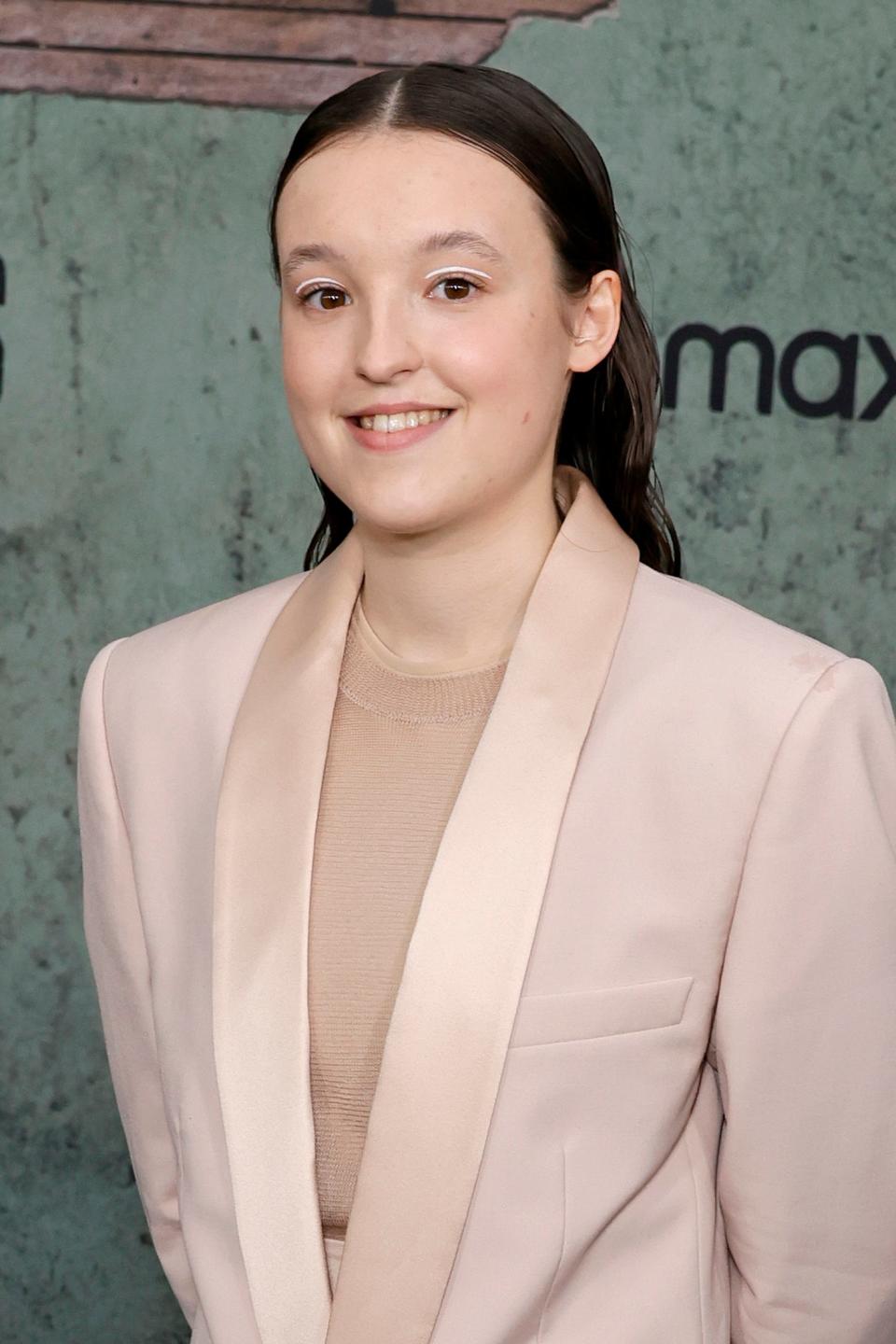 Bella Ramsey poses in a pale suit at 'The Last of Us' event