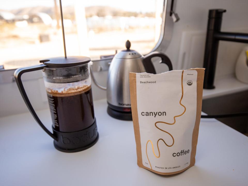 Coffee grounds and a kettle by a full French press.