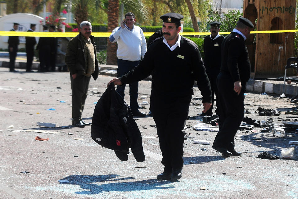 An Egyptian policeman carries a jacket at the scene of a damaged bus after a deadly explosion Sunday near the Egyptian border crossing with Israel in Taba, Egypt, Monday, Feb. 17, 2014. An explosion tore through a bus filled with South Korean sightseers in the Sinai Peninsula on Sunday, killing at least four people and raising fears that Islamic militants have renewed a bloody campaign to wreck Egypt’s tourism industry. (AP Photo/Nameer Galal)